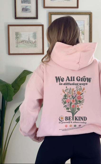 Blush pink Be Kind hooded sweatshirt with a floral design that includes embroidery and screenprinting elements